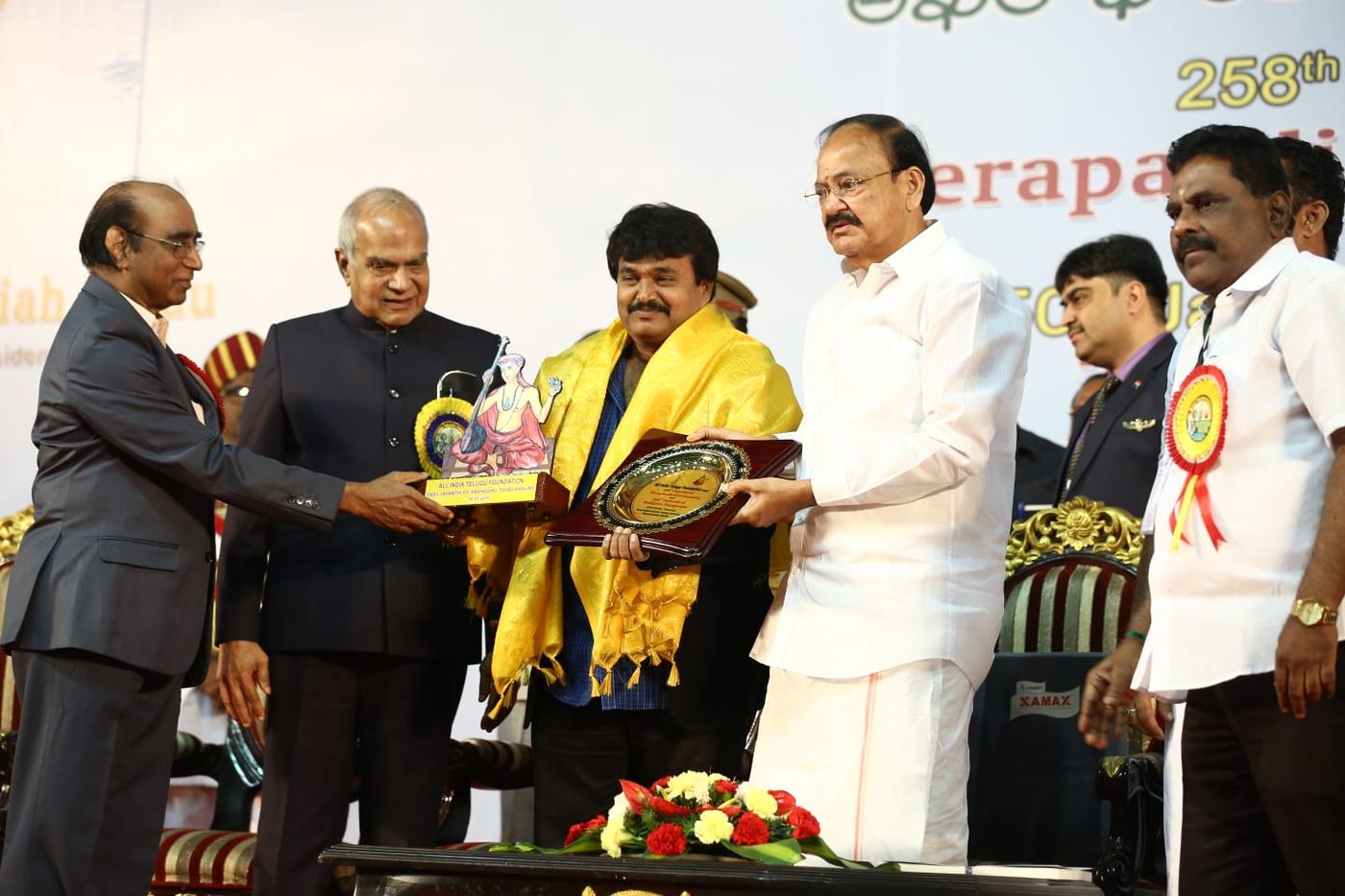 Ramu receiving an honour on stage from the All India Telugu Foundation
