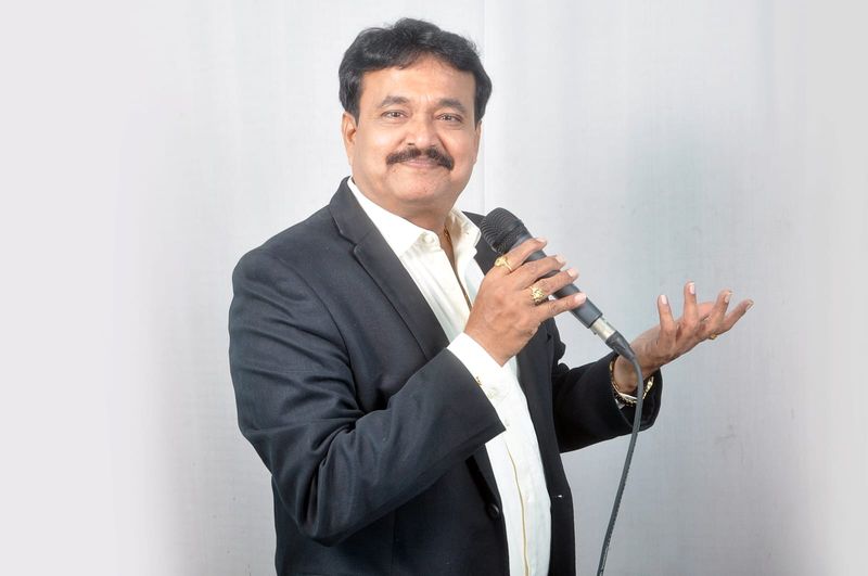 Ramu Maharajapuram, studio portrait, black blazer, gesturing