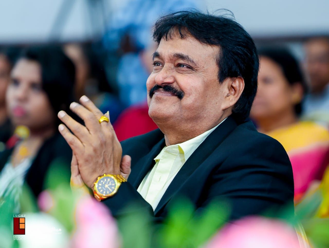 Ramu Maharajapuram smiling and clapping in front of an audience