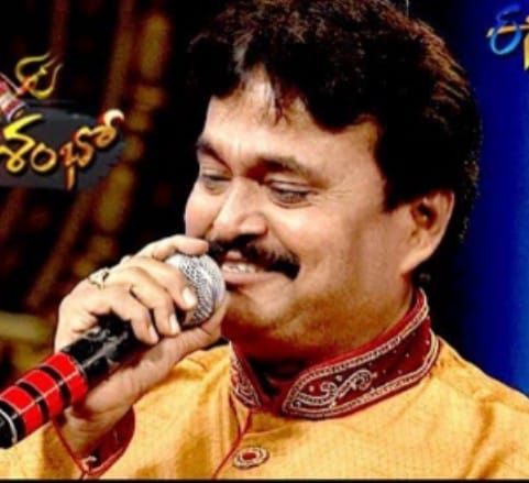 Close-up of Ramu singing in an orange kurta