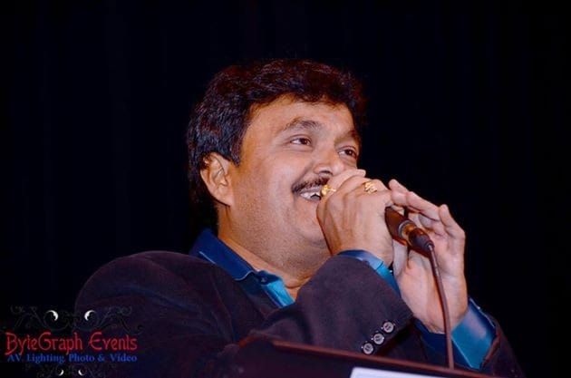 Ramu singing into a microphone under stage lights
