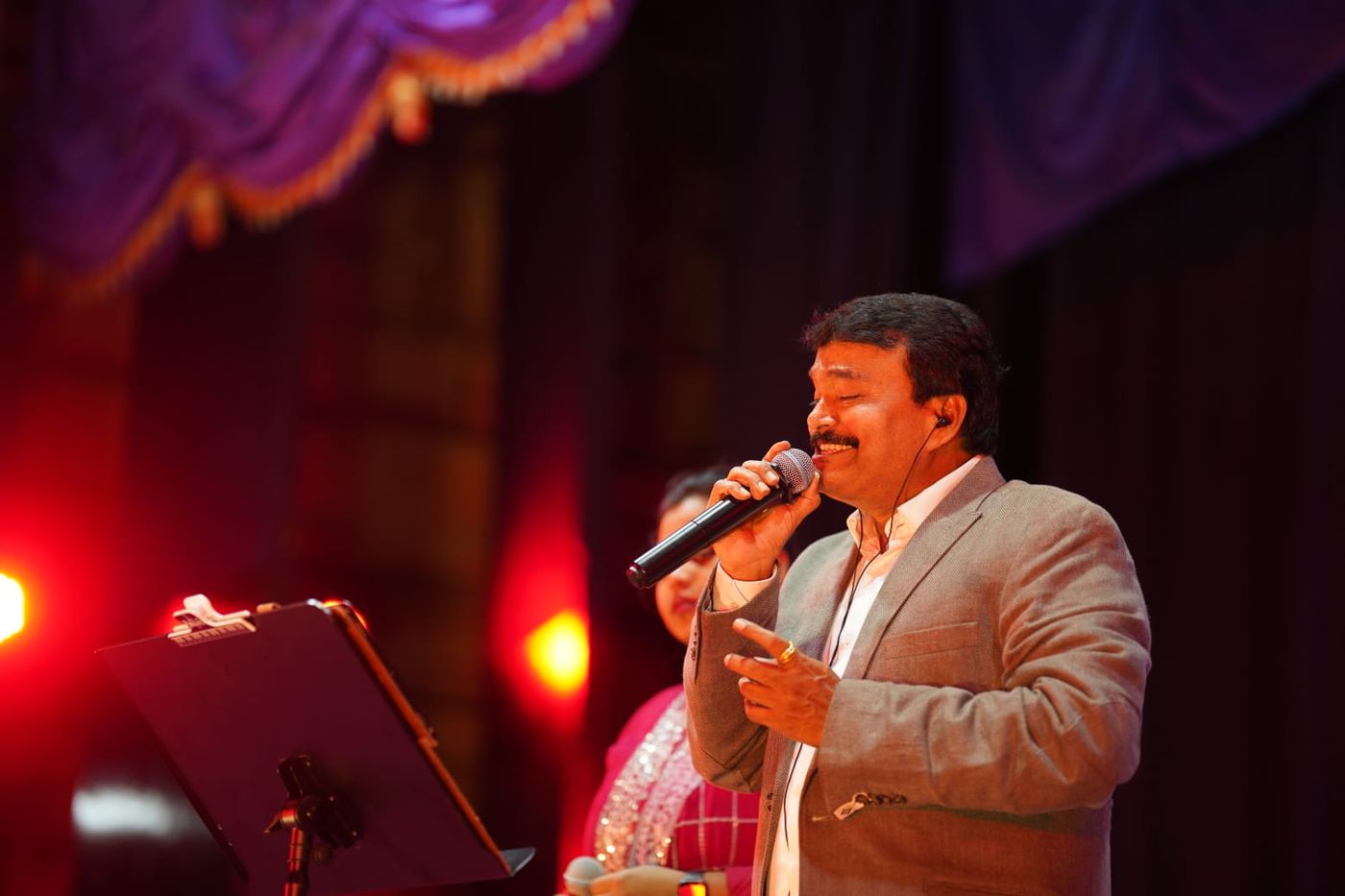 Ramu singing under red stage lights